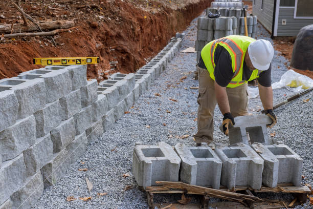 5 signs of retaining wall failure in Canonsburg, PA Construction site worker installing newly constructed large block retaining wall construction near new home